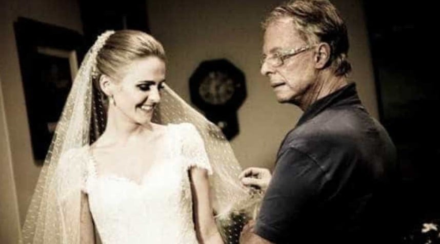 Foto do estilista brasileiro Guilherme Guimarães a segurar o véu de uma modelo vestida de noiva
