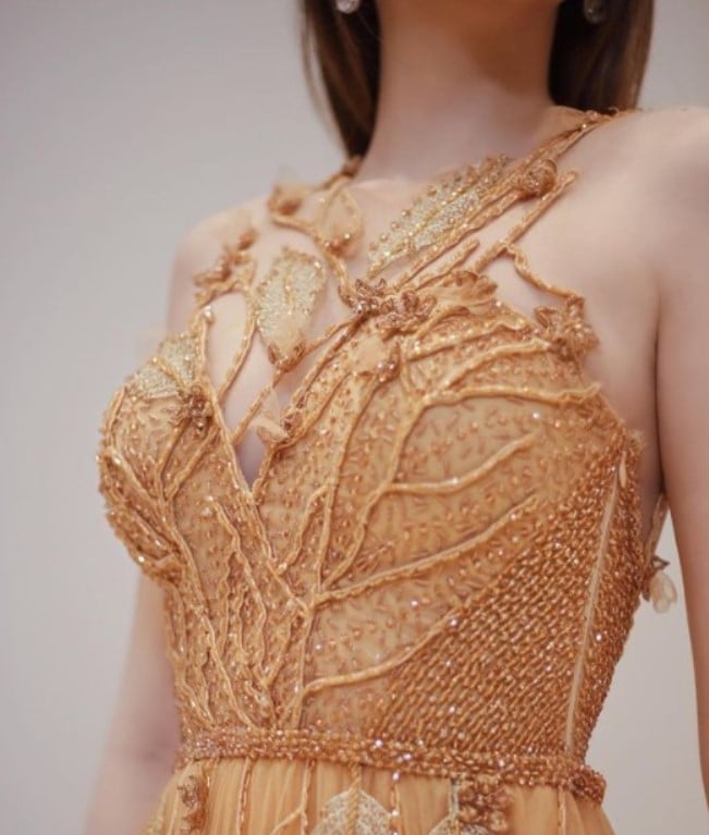 Foto da parte superior de uma modelo posando com um vestido dourado de Ivanildo Nunes