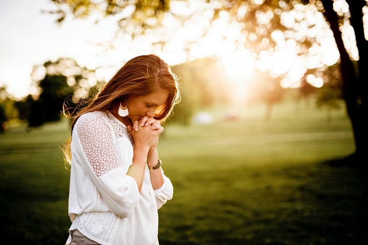 foto de mulher com cabeça baixa e mãos em oração