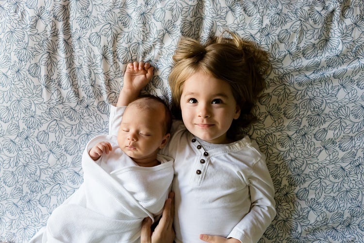 Foto de bebê e menina deitados na cama