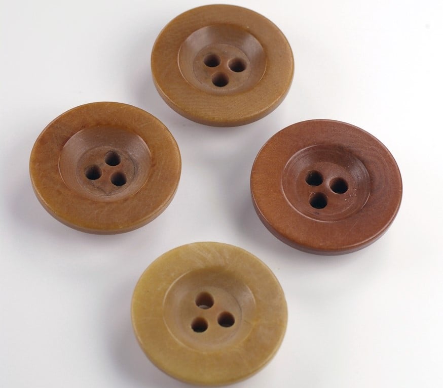 Foto de 4 botões de 3 furos feitos com marfim vegetal em fundo branco