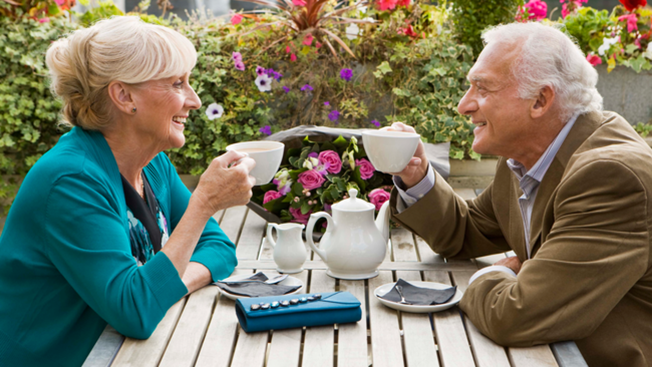 Casal de idosos conversando e sorrindo enquanto tomam chá