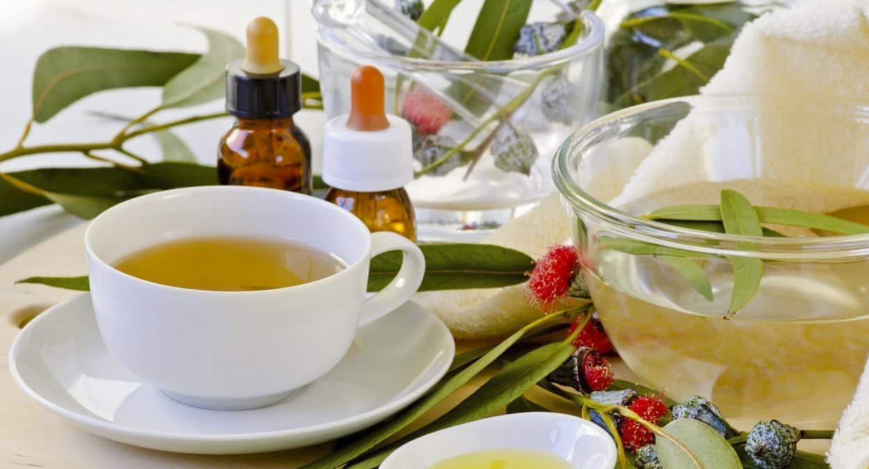 Mesa com chá, óleo e folhas de eucalipto