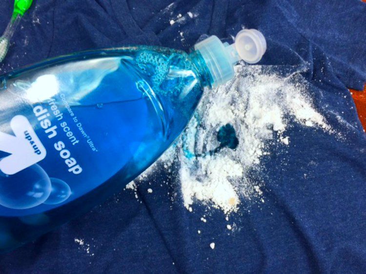 Detergente e bicarbonato sobre uma roupa azul escuro para remover mancha de óleo