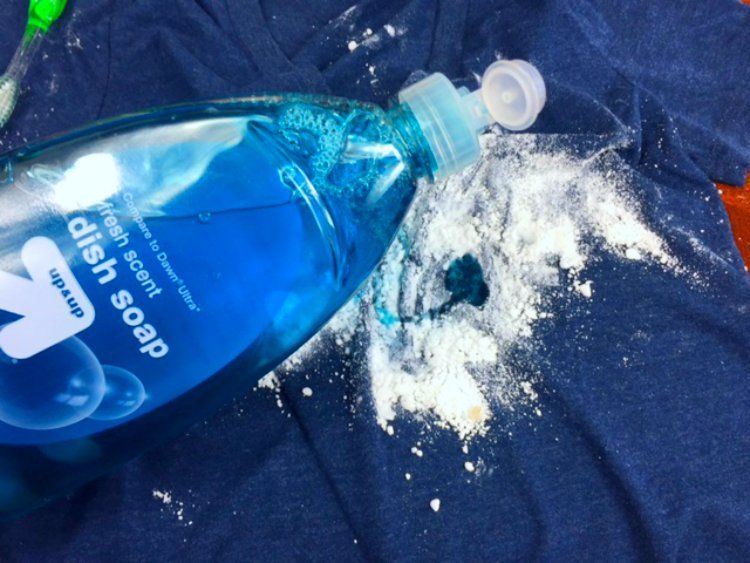 Detergente e bicarbonato Detergente e bicarbonato sobre uma roupa azul escuro para remover mancha de óleo