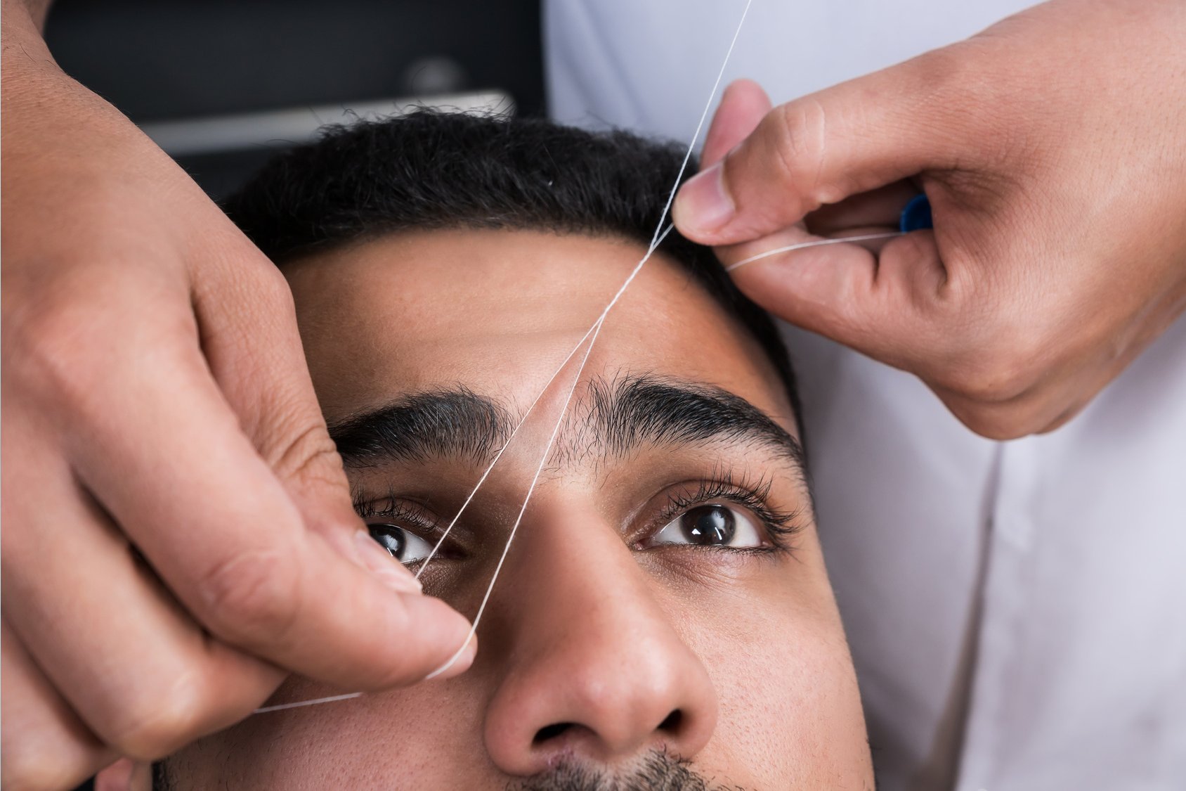 Homem recebendo procedimento de depilação egípcia nas sobrancelhas