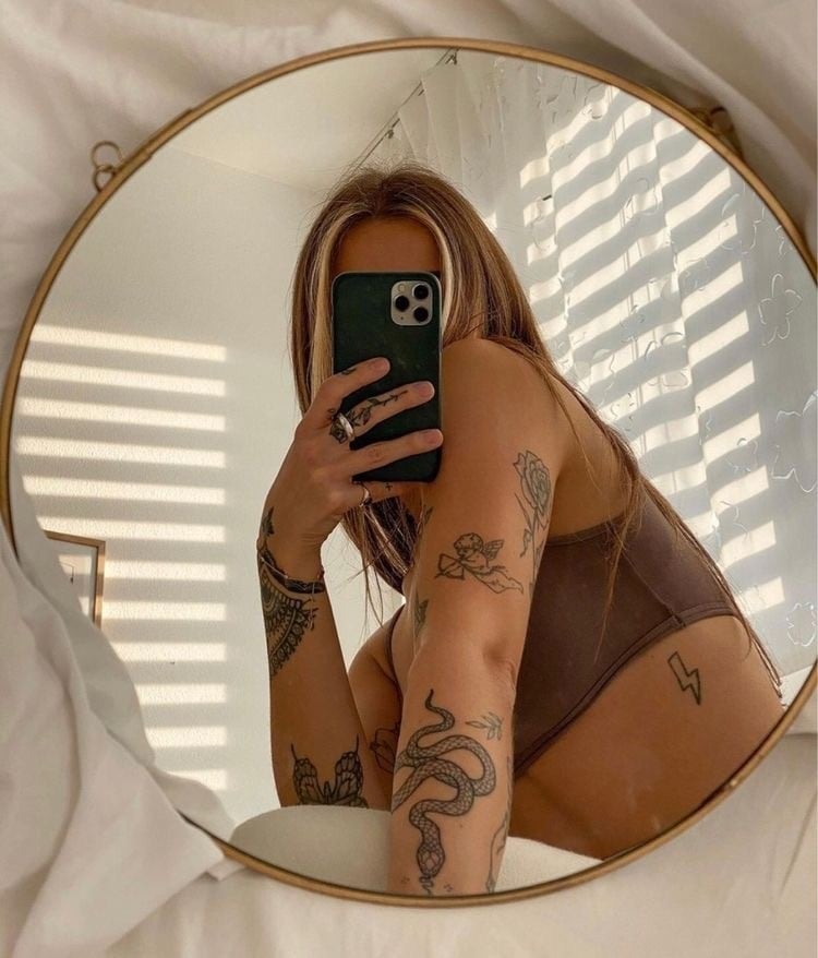 mulher tatuada tirando foto no espelho