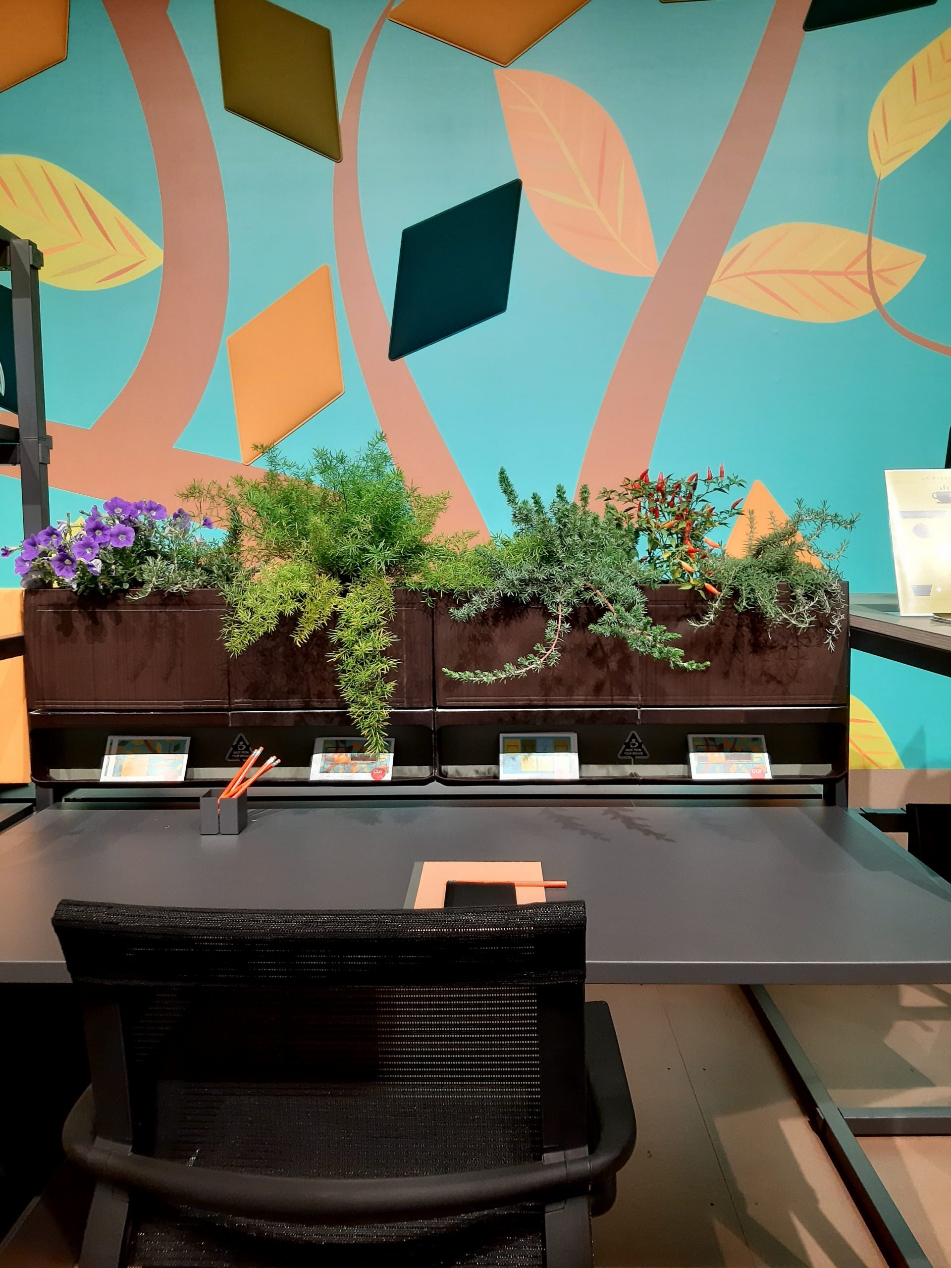 Proposta de home office com jardineira de plantas naturais na parte superior da estação e cadeira ergonômica