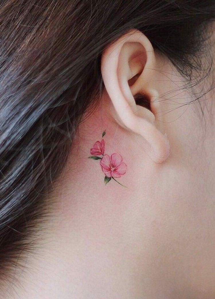 Tatuagem feminina atrás da orelha com flores