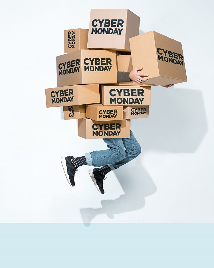 Foto de pessoa segurando caixas de papelão onde se lê “Cyber Monday”