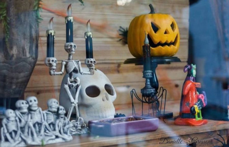 Vitrine com enfeites de Halloween: caveira, candelabro, abóbora, chapéu de bruxa e o drácula 