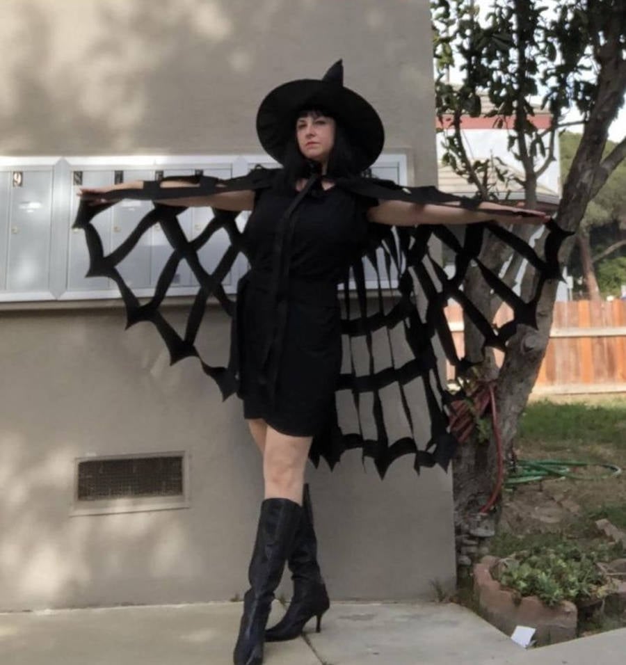 Imagem de uma mulher fantasiada de bruxa para o Halloween com uma capa de Teia de Aranha