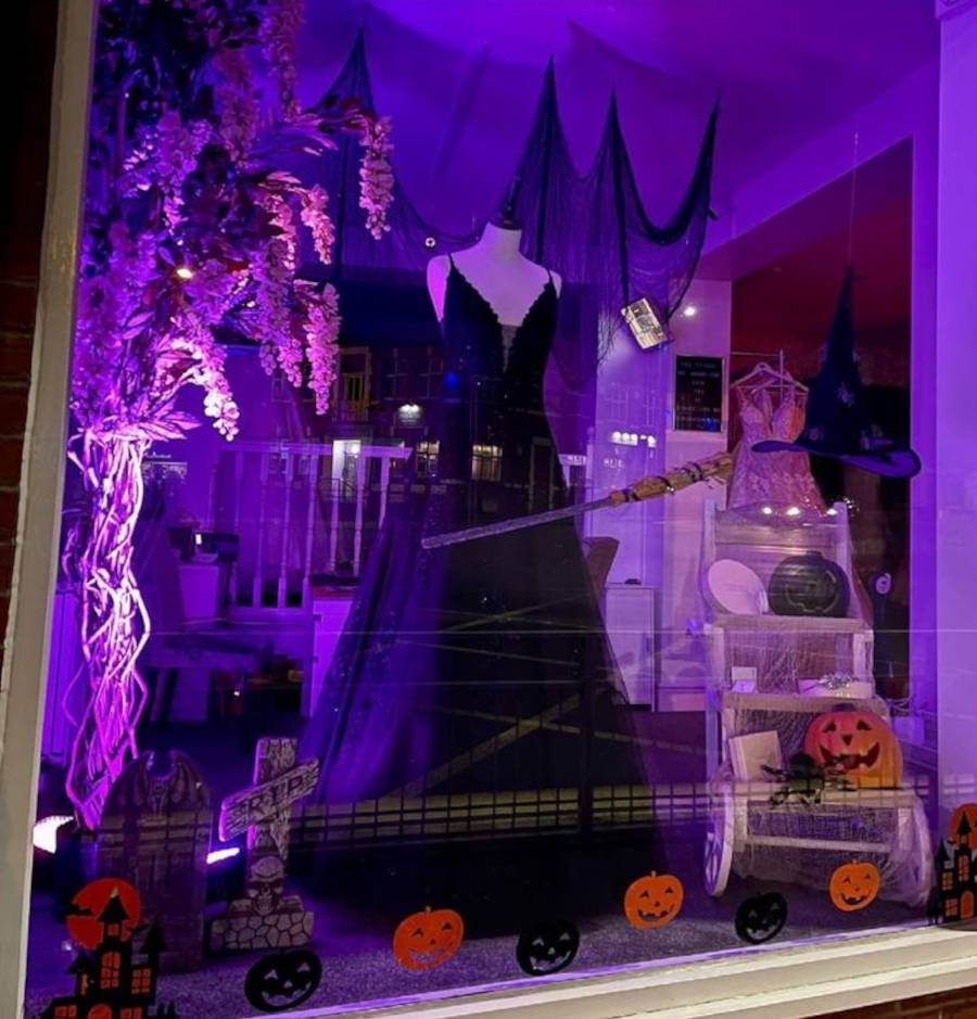 Foto de uma vitrine de Halloween iluminada com luzes roxas e enfeitos típicos de Halloween