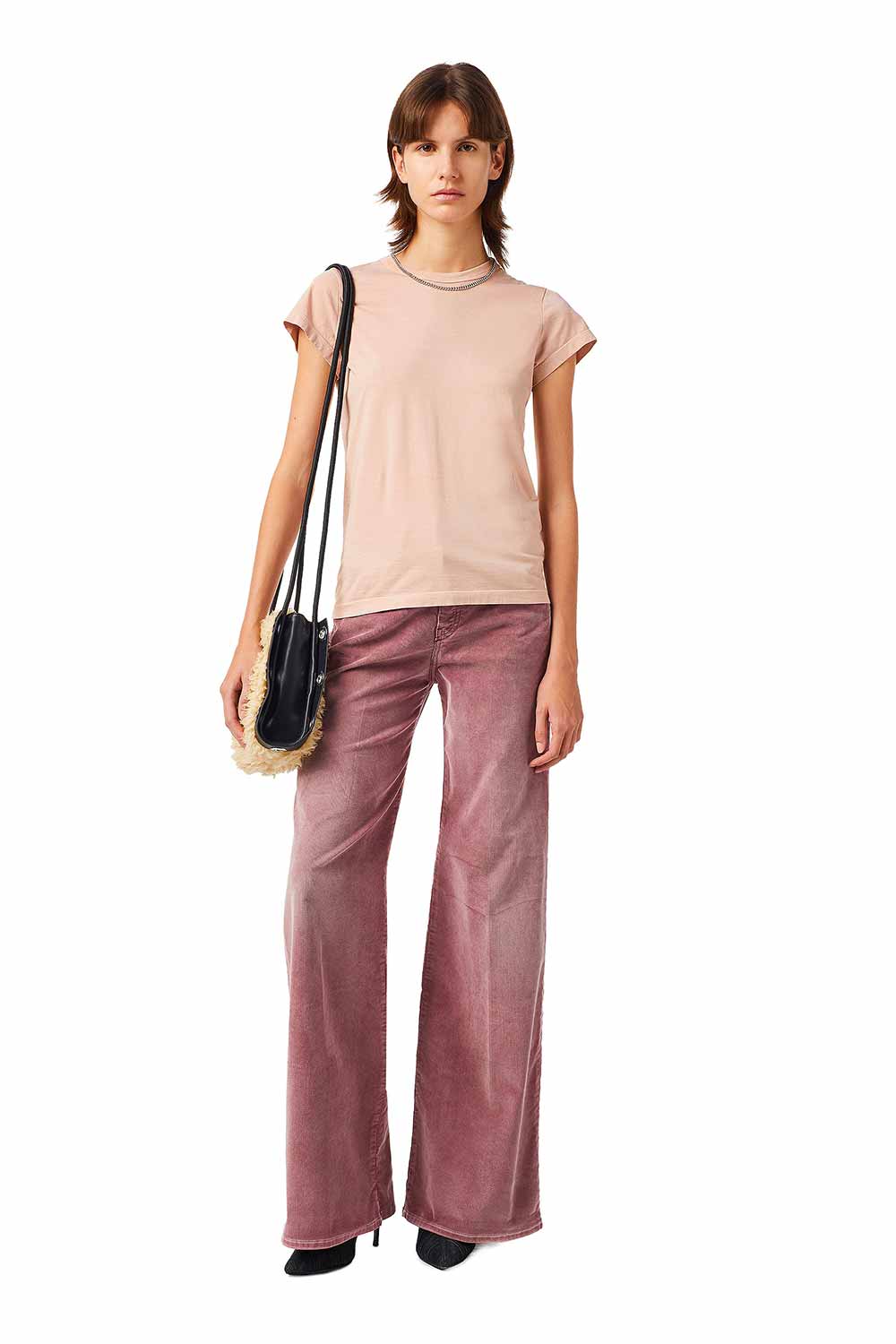 modelo vestindo Look marca Diesel em jeans colorido tom de beterraba bem como t-shirt rosa bolsa e sapatos pretos