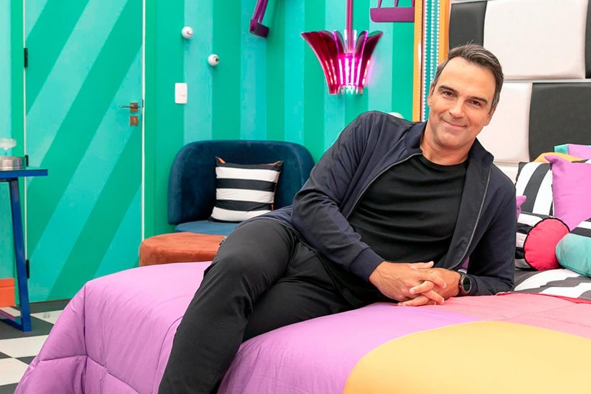 Tadeu de roupa preta deitado em cama do quarto do líder do BBB todo colorido
