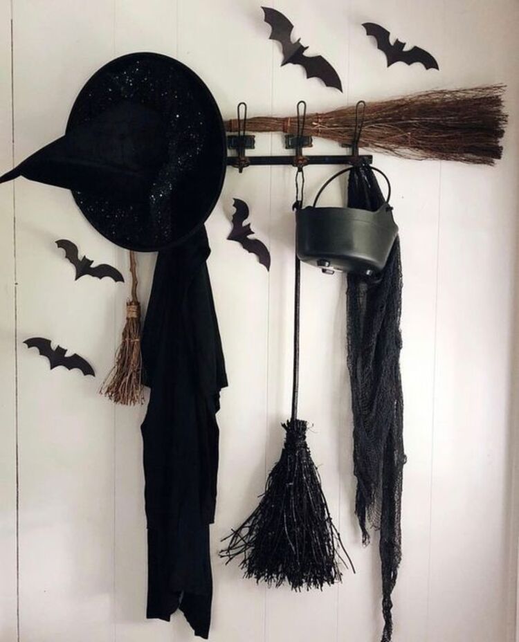 Chapéu de bruxa, vassoura, caldeirão e roupa em ganchos na decoração de Dia das Bruxas