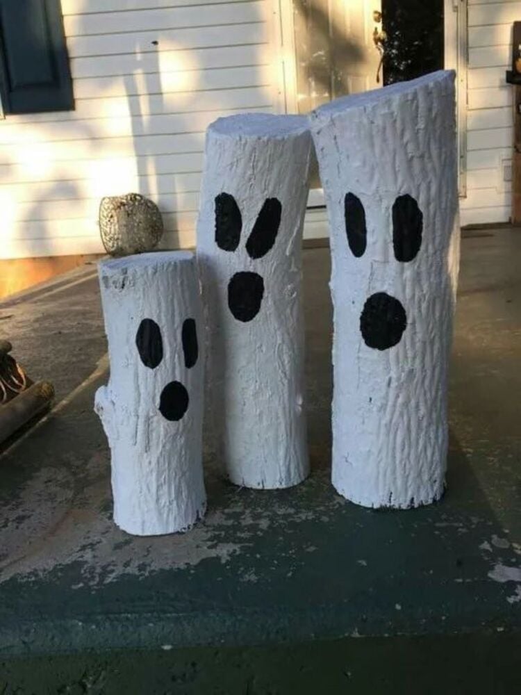 Decoração simples de Halloween para jardim: tocos de madeira pintados de branco e com caras de fantasmas