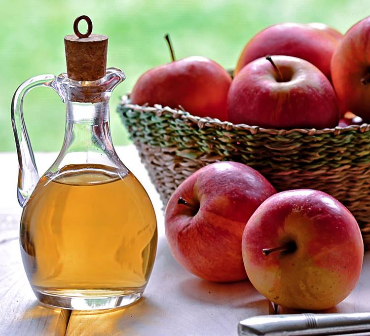 Foto de vinagre de maça ao lado de cesta com maçãs