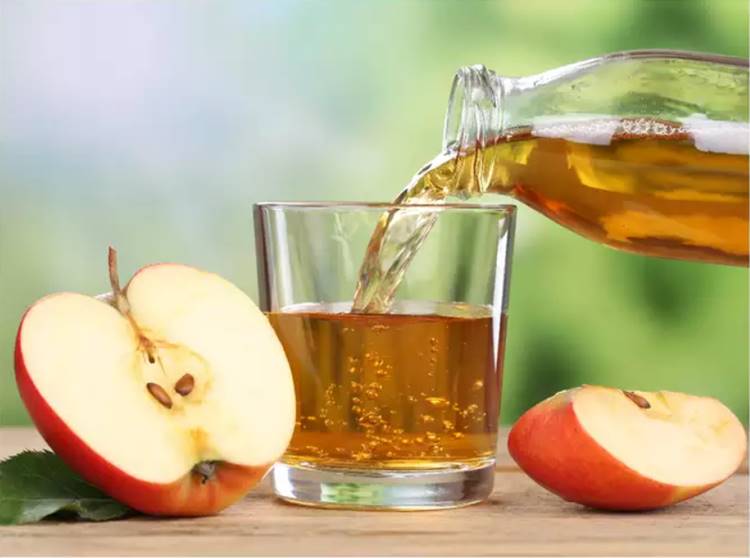 Foto de vinagre de maça em copo com maçãs picadas ao lado