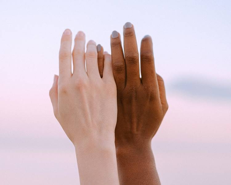 Foto de mãos de pessoas negra e branca.