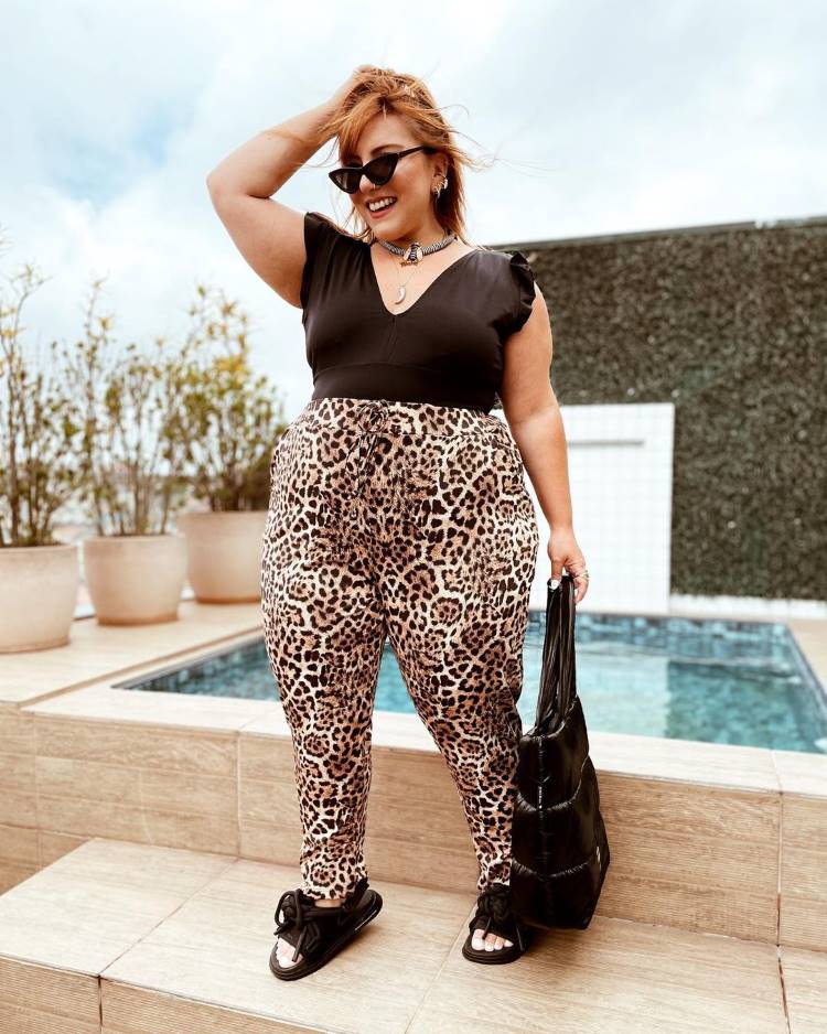 Estampas verão 2022; mulher usa calça de onça, blusa, bolsa e chinelo preto Estampas verão 2022