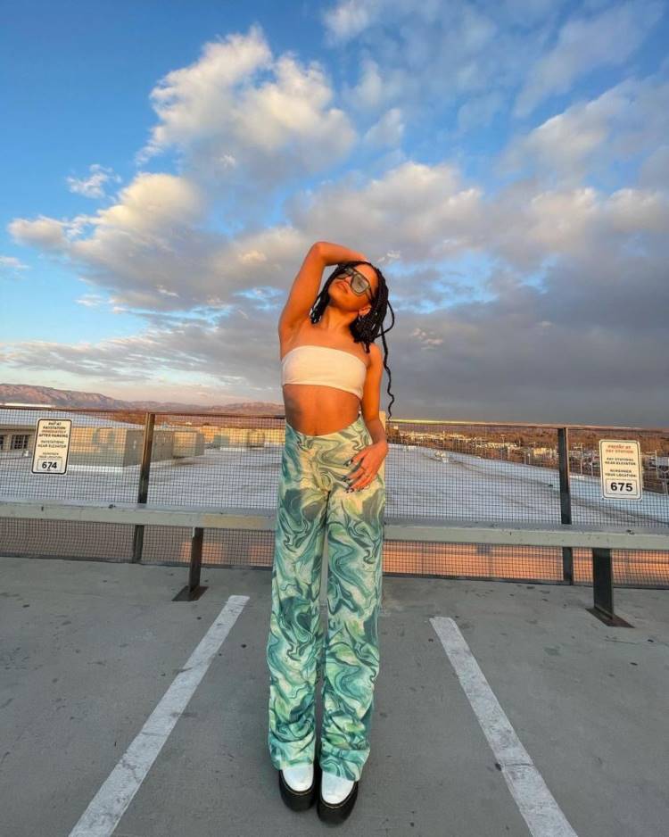 Estampas verão 2022: mulher usa calça com estampa psicodélica verde e top branco Estampas verão 2022