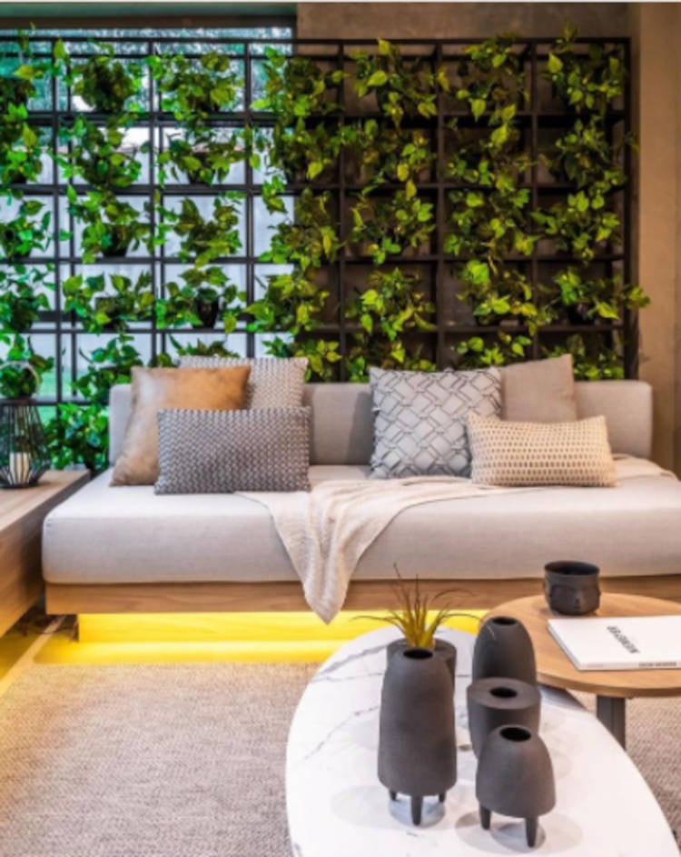 Sala com sofá e parede forrada de plantas.