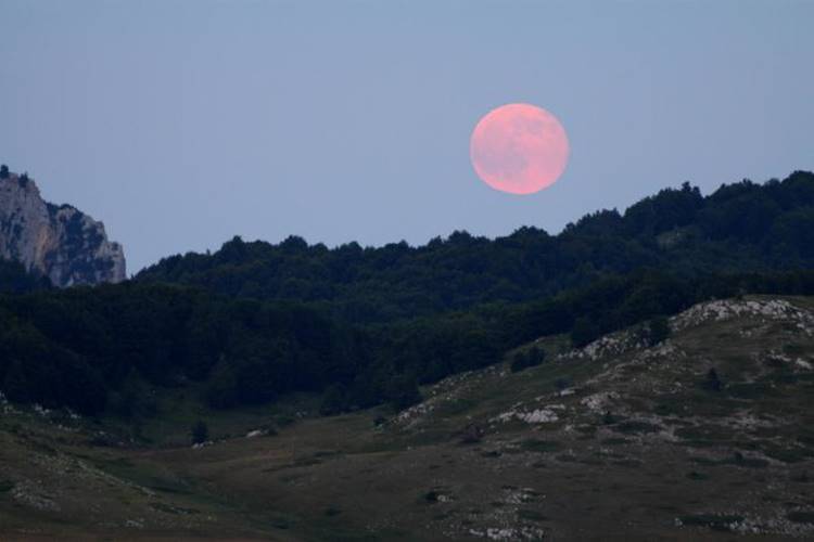 Fenônemo superlua rosa avistado entre montanhas. Foto do fenônemo superlua rosa.