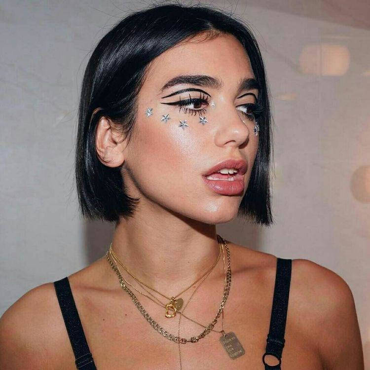 Dua Lipa usando delineado gráfico preto e adesivos prateados de estrela
