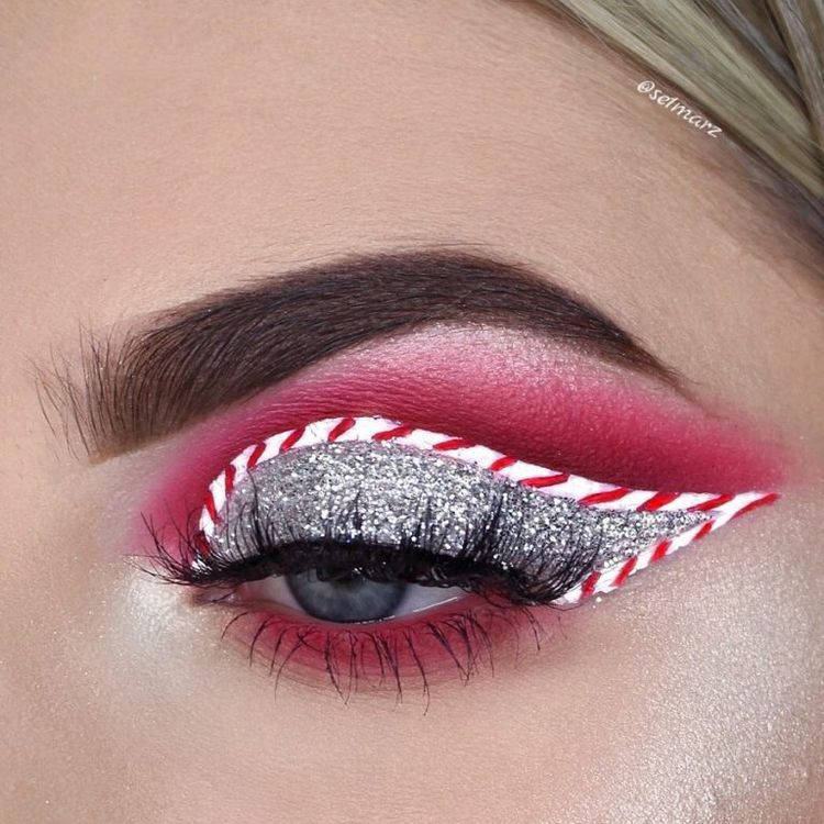 Zoom em olho de mulher de pele clara com sombra vermelha, prateada e delineado branco e vermelho imitando bengala doce
