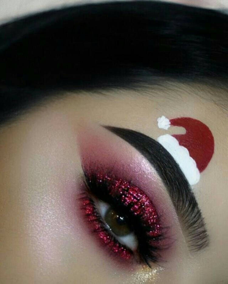 Zoom em olho com sombra vermelha com glitter e desenho de gorro do papai noel acima da sobrancelha