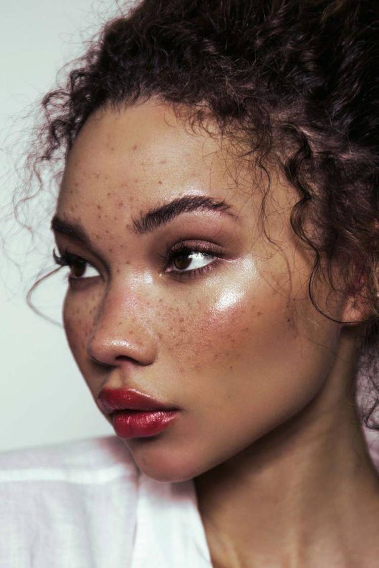 Mulher de pele clara com sardas, sombra terrosa, gloss e pele iluminada