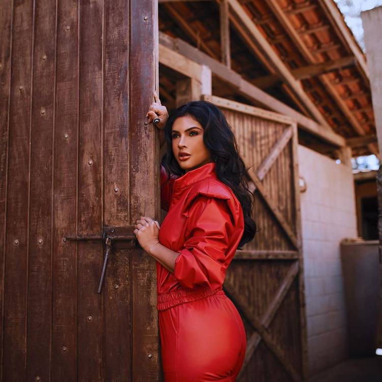 Mileide, peoa de A Fazenda 13, com roupa vermelha na porta de um celeiro. Foto de Mileide Mihaile