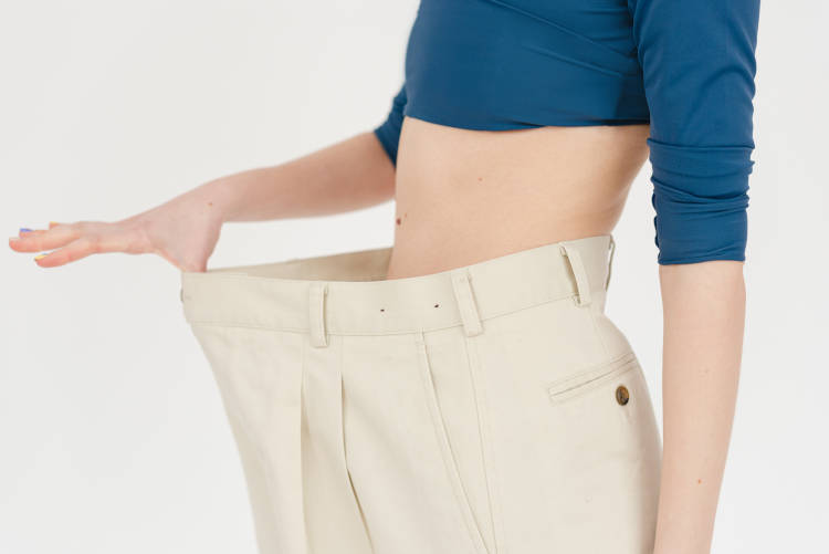 Mulher com calça larga após perder barriga.