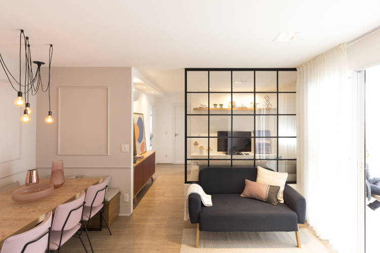 Sala de estar com sofá preto. Parede com moldura boiserie.