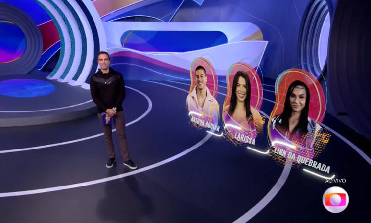 Tadeu em pé no estúdio com as fotos de Arthur, Larissa e Lina atrás. Sexto paredão foi formado no Big Brother Brasil