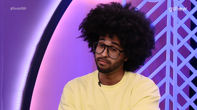 Luciano é negro, tem cabelo black power, usa óculos de grau e veste uma blusa amarela. Luciano está com Covid-19