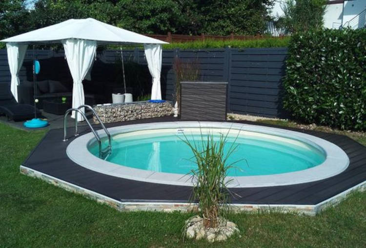 Área de lazer com piscina redonda e tenda. Deck preto.