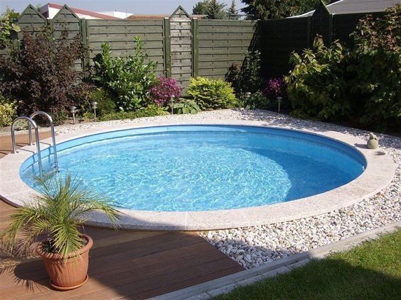 Quintal com grama, jardim e piscina. Seixos brancos no quintal.