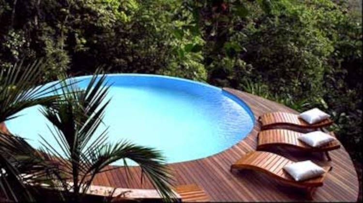 Piscina redonda com deck de madeira. Paisagem com piscina.