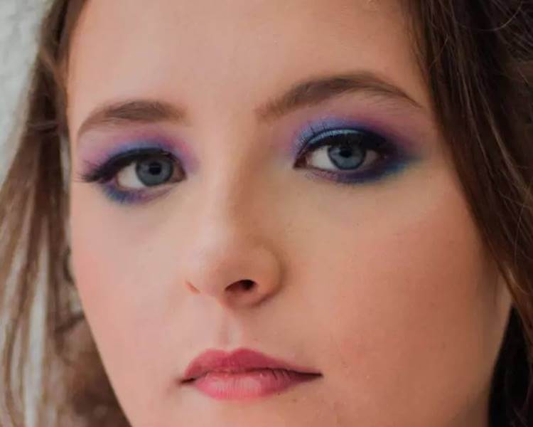 Foto de modelo com maquiagem sombra azul.