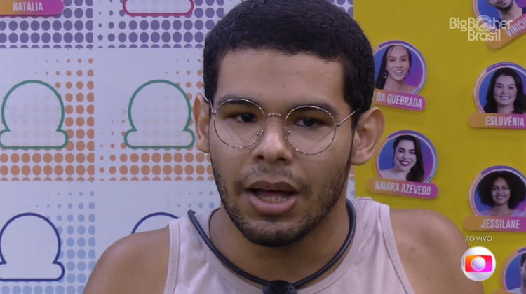 Vinicius usa óculos de grau, tem cabelo preto, batido, e usa regata. Vinicius pode estar com Covid-19 no BBB 22