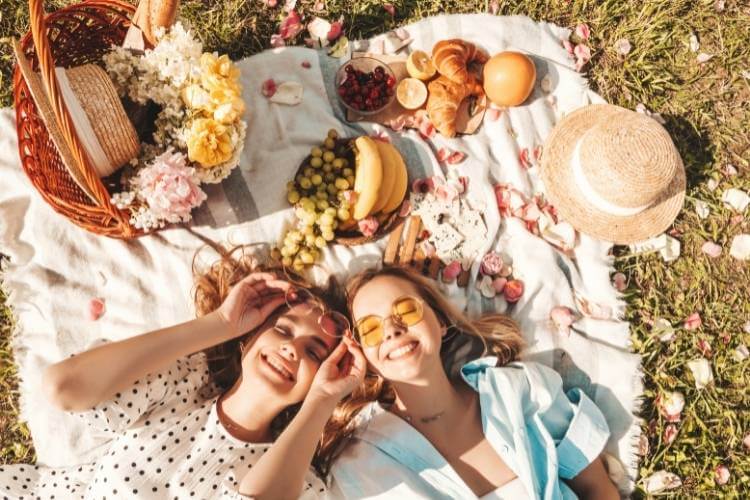 duas mulheres fazendo piquenique com frutas e pães piquenique