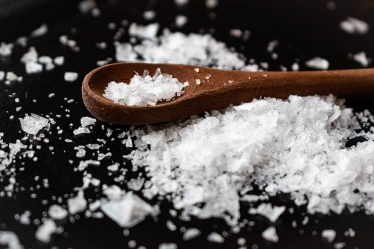 colher de pau com sal grosso espalhado em superfície preta colher de pau com sal grosso