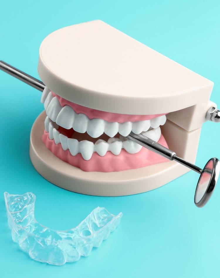 dentadura, protetor e espelho de dentista em fundo azul Objetos usados por dentista.