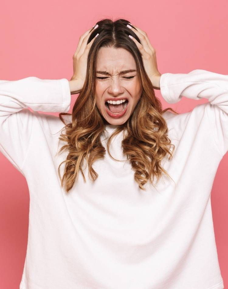 mulher estressada com as mãos na cabeça Estresse causa bruxismo.