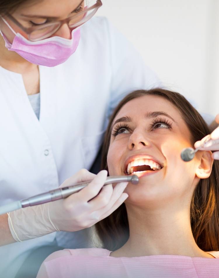 dentista de máscara rosa avaliando dentes de paciente Pessoa passando por uma consulta no dentista.