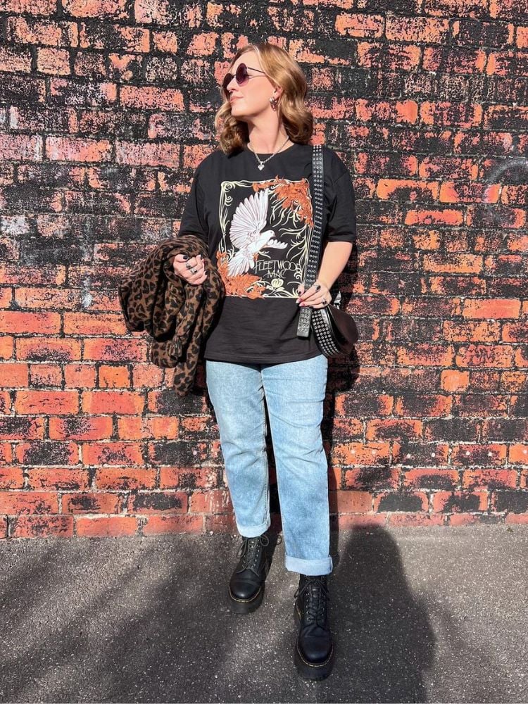 mulher usando camiseta de banda com calça jeans reta e coturno.