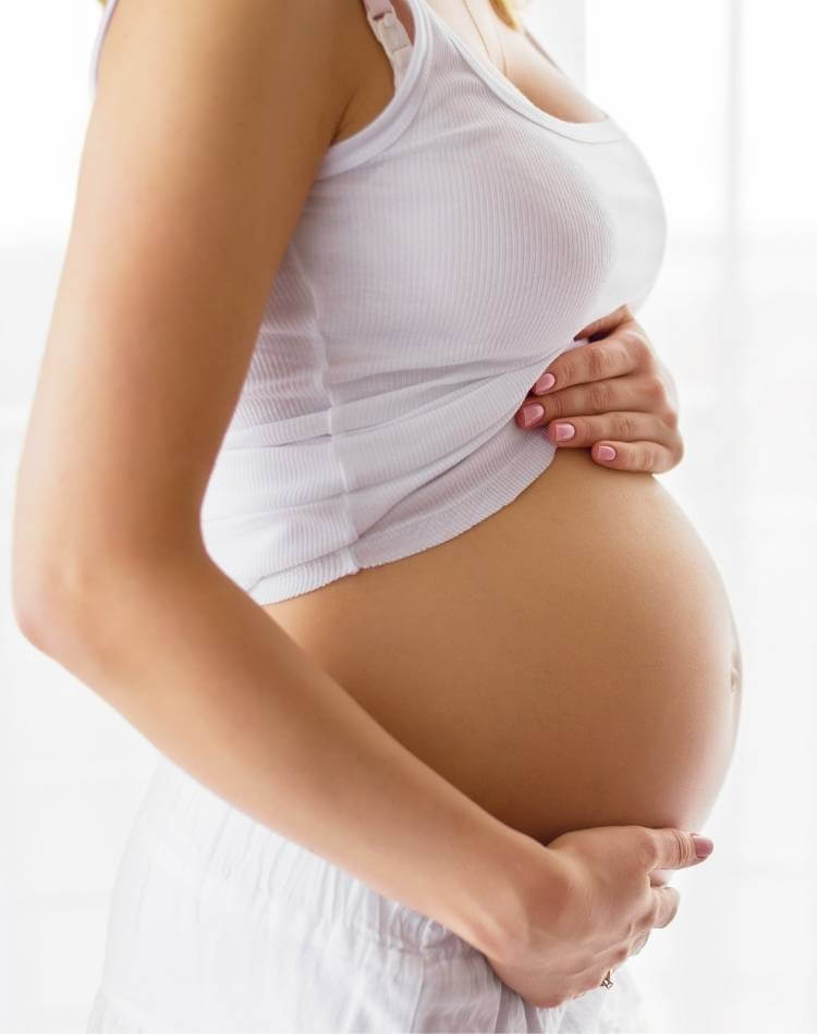 Grávidas não podem tomar chá de arruda. Mulher grávida com regata levantada expondo a barriga.