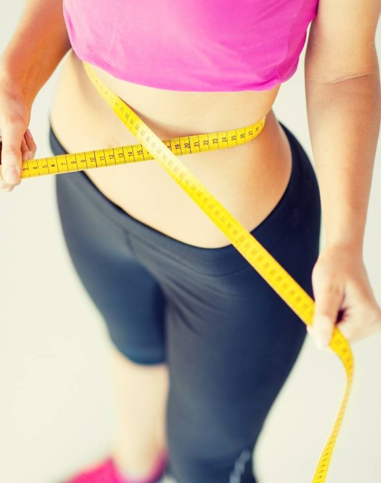 Resultado dos chás para desinchar. Mulher medindo a barriga com fita métrica.